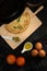 Omelet pieces on a wooden cooking desk with olives, egg yolk, tomatoes, and fresh eggs on the sides