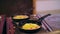 Omelets, fried eggs, cooked on the stove in two greasy, dirty, pans. stove is dirty too. over the pans you can see a