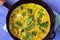 Omelette with broccoli, herbs and sesame seeds in frying pan.