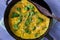 Omelette with broccoli and herbs, toasted with sesame seeds on frying pan.