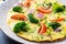 Omelette with broccoli, tomatoes and red onions on dark table.