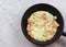 Omelette with sausages, green onions, cheese and croutons on frying pan on a light gray background