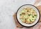 Omelette with sausages, green onions, cheese and croutons on a white round plate on a light gray background