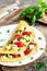 Omelette stuffed with cheese, fresh tomatoes and parsley. Stuffed omelette on a plate and on old wooden background