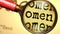 Omen - abstract concept and a magnifying glass enlarging English word Omen to symbolize studying, examining or searching for an