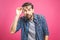 OMG! It`s incredible! Portrait of handsome young man in glasses looking at camera while standing against pink background. Close u