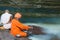 Omkareshwar, India - November 25, 2017: Sadhu pouring milk into holy Narmada river at Omkareshwar, Madhya Pradesh, India.