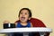 One 1 year old baby boy learning to eat alone smiling happy but messy on baby dining chair at home