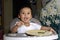 One 1 year old baby boy learning to eat alone smiling happy but messy on baby dining chair at home