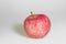 One apple on white background. Red juicy ripe apple close up. Fresh striped fruit. Side view