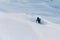 One-armed male snowboarder going down a snowy slope, on a snowboard