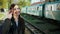 One beautiful and happy girl standing in front of the train carriage holds a ticket in her hands and says goodbye to her