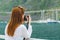 One beautiful readhead girl with camera make photo of the marina in the sunshine. Woman shooting travel photo on Canary