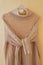 One beige pastel knit warm sweater with knotted sleeves on hanger