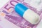 One big blue and white pill is laying on 500 euro banknote