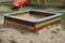 One big colored square wooden sandbox with white sand