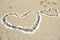 One big heart made of stones and white seashells next to small heart on beach of the Japanese sea.