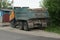 One big old green dump truck stands on a gray asphalt road