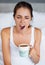 One big YAWN. A young woman giving a big yawn while sitting with a cup of coffee in bed.