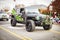 One black and green jeep driving through a Christmas parade