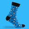 One blue sock with a guitar print, on a blue background, surround sock with a shadow
