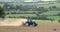 One blue tractor processes and sows a plowed field in summer. Agricultural work in the