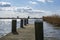 One of the boat docks with mooring posts in the lake de Rottemeren with the windmill Tweemanspolder nr 4 in the background on a su