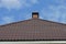 One brick metal chimney on the brown tiled roof