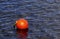 One bright orange buoy floating on lake water