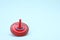 One bright spinning top on light blue background, space for text. Toy whirligig