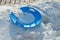 One broken round blue plastic sled plate lies on a snowdrift