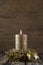 One burning golden advent candle on wooden rustic background.