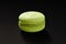 One cake of macaroni green color. Delicious pistachio macaroon isolated on black background. French sweet cookie