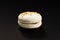 One cake of macaroni white color. Delicious caramel macaroon isolated on black background. French sweet cookie