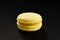 One cake of macaroni yellow lemon color. Delicious macaroon isolated on black background. French sweet cookie