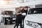 It is the one car I want! Beautiful young couple standing at the dealership choosing the car to buy