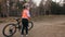 One caucasian children rides bike road track in dirt park. Girl riding black orange cycle in racetrack. Kid goes do