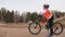 One caucasian children rides bike road track in dirt park. Girl riding black orange cycle in racetrack. Kid goes do