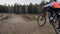 One caucasian children rides bike road track in dirt park. Girl riding black orange cycle in racetrack. Kid goes do