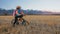 One caucasian children walk with bike in wheat field. Little girl walking black orange cycle on background of beautiful
