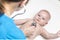 One caucasian female doctor is listening heartbeat of infant boy by stethoscope