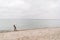 One caucasian man young caucasian woman tourist with a black backpack on a sandy beach near the Baltic sea in winter. Theme trip