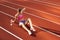 One Caucasian woman, female athlete, runner training at public stadium, sport court or palyground outdoors. Summer sport