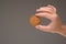 One cereal multigrain raw cookie held in hand by Caucasian male hand. Close up studio shot,  on gray