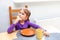 One child, small girl finishing her meal, taking one last bite using fork eating by herself. Sitting on a chair