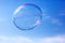 One clean soap bubble flying in the air, blue sky.