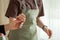 One cook passes a kitchen brush to another cook in a green apron