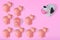 One cow in front of several small cute pigs on pastel pink background