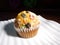 One cupcake muffin with sliced fruit spread on a rectangular white plate.