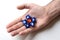 One dice with the symbol hammer and sickle surrounded by five blue cubes with the symbol usa star are on a man`s palm.